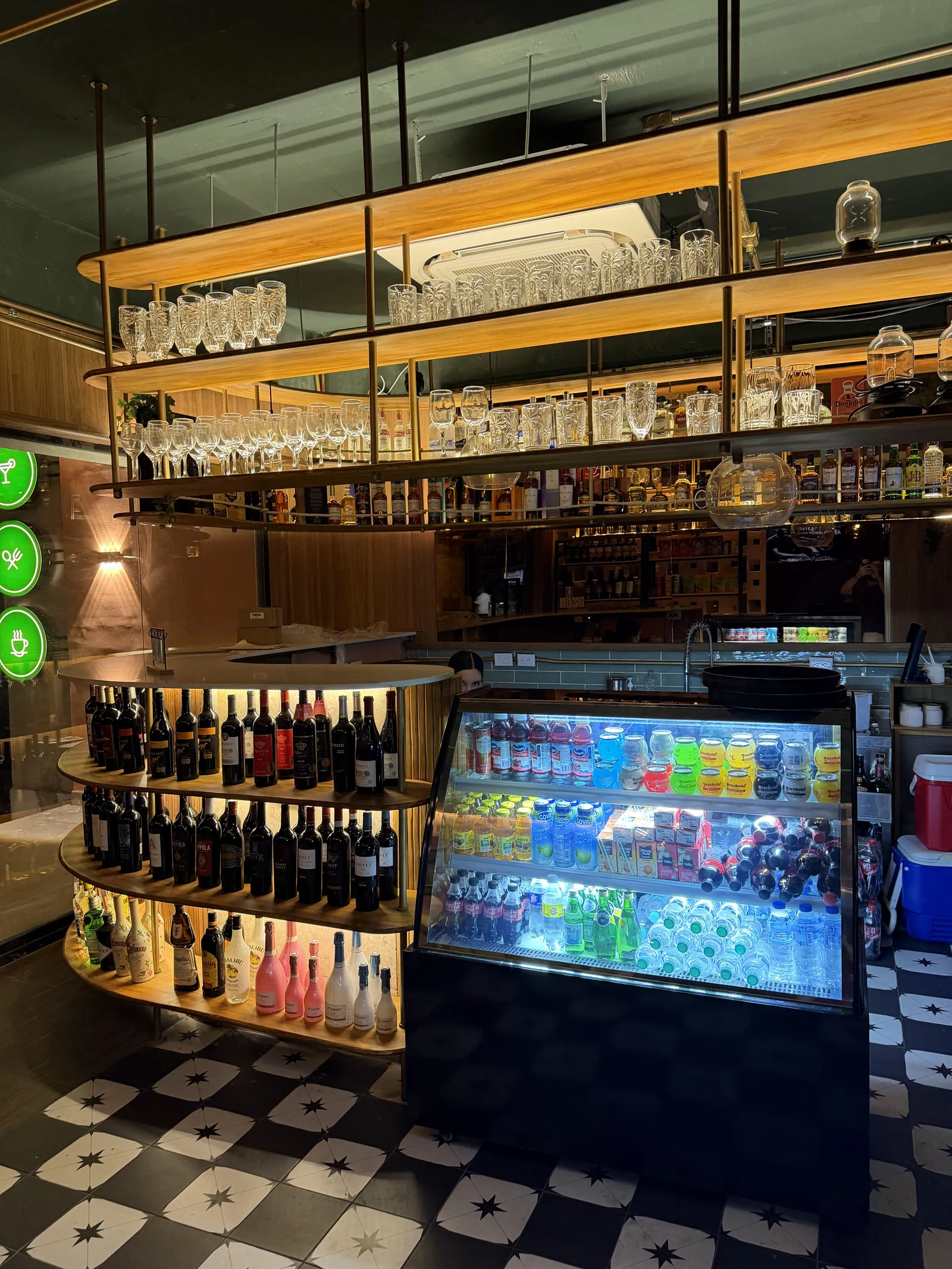 Floor-to-ceiling shelves with glassware, wine and a drinks cooler